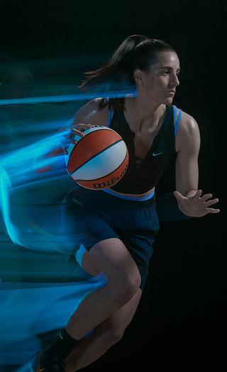Caitlin Clark dribbling a basketball with dynamic blue light trails against a dark background